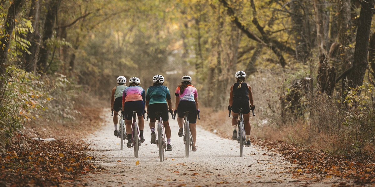 Gravel riders on a tree-lined Arkansas trail in autumn
